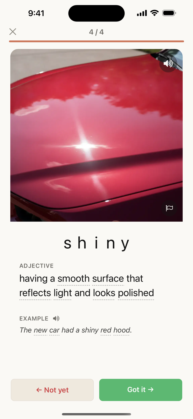 A study card for “shiny,” with a photo of a glossy red car hood catching the light beside a plain-English definition and an example sentence.